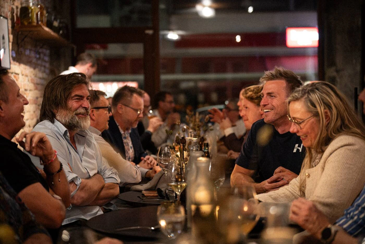 Gæster griner sammen ved det lange bord i Founders Food Club